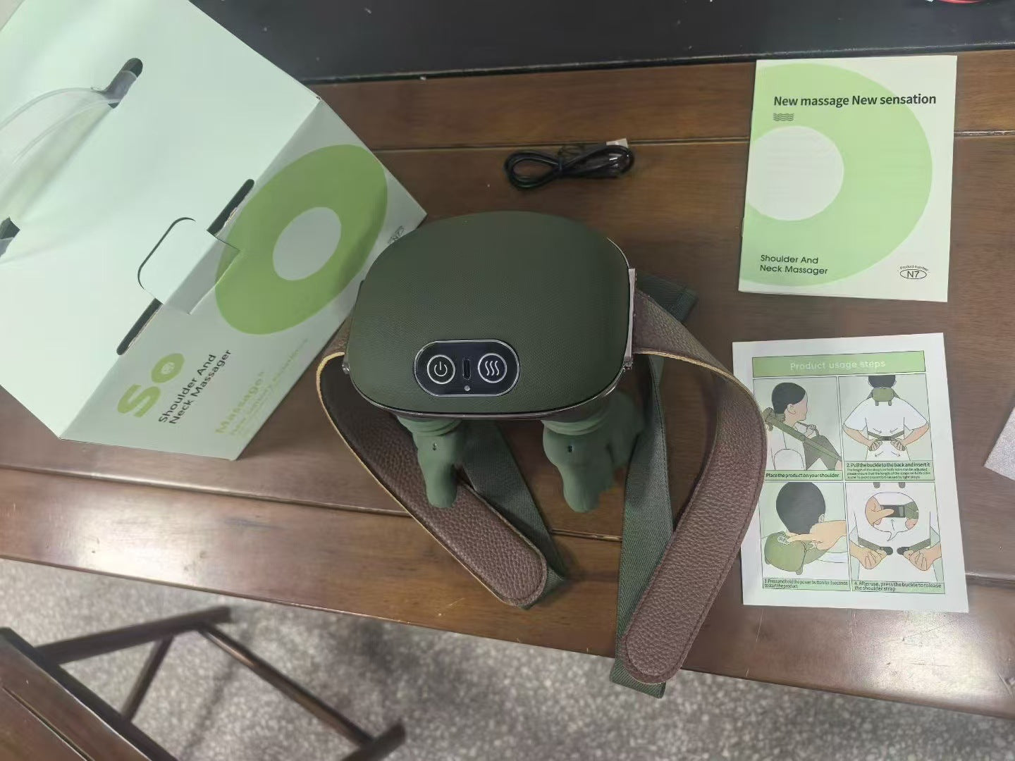 Green massage device with accessories on a wooden table