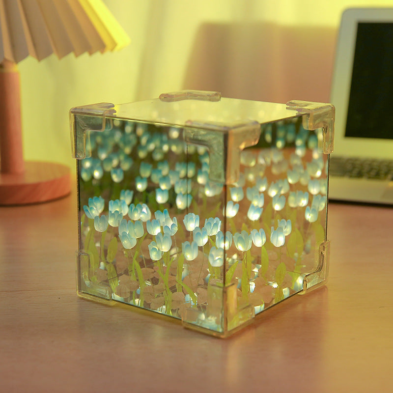 Clear cube with glowing blue and green lights on a wooden surface.