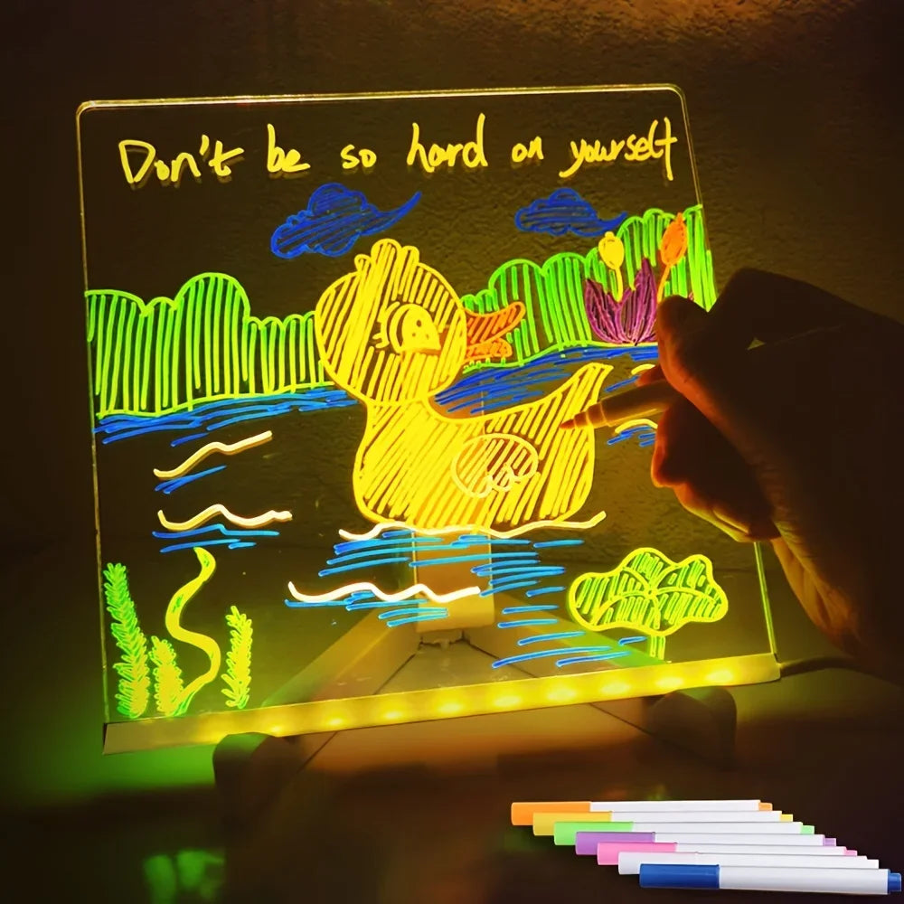 Light-up drawing board with colorful drawing and text 'Don't be so hard on yourself' in a dark setting.