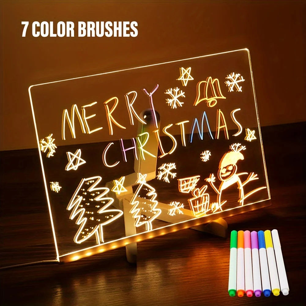 Light-up board with Christmas drawings and 7 color brushes on a wooden surface.