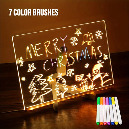 Light-up board with Christmas drawings and 7 color brushes on a wooden surface.