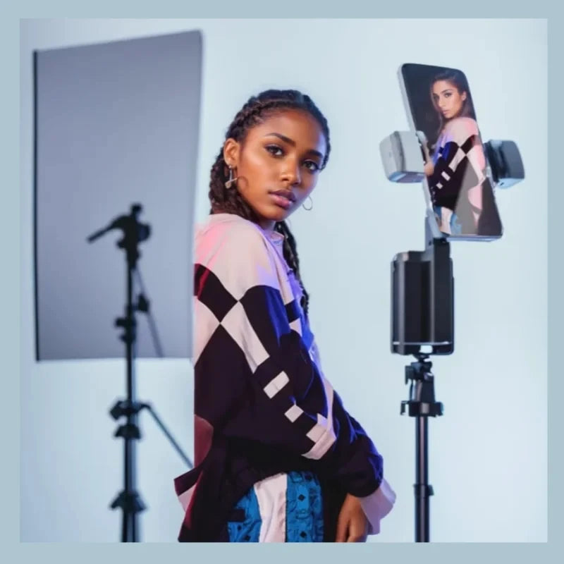 Woman posing in front of a camera on a tripod with a light panel in the background