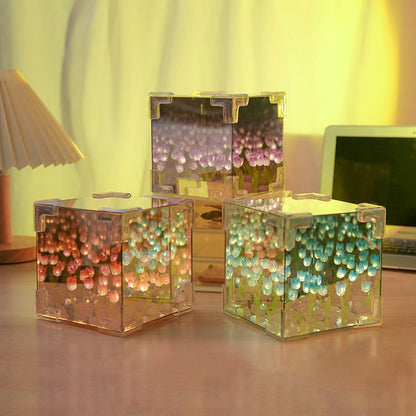 Three transparent cube containers with colorful beads on a desk.